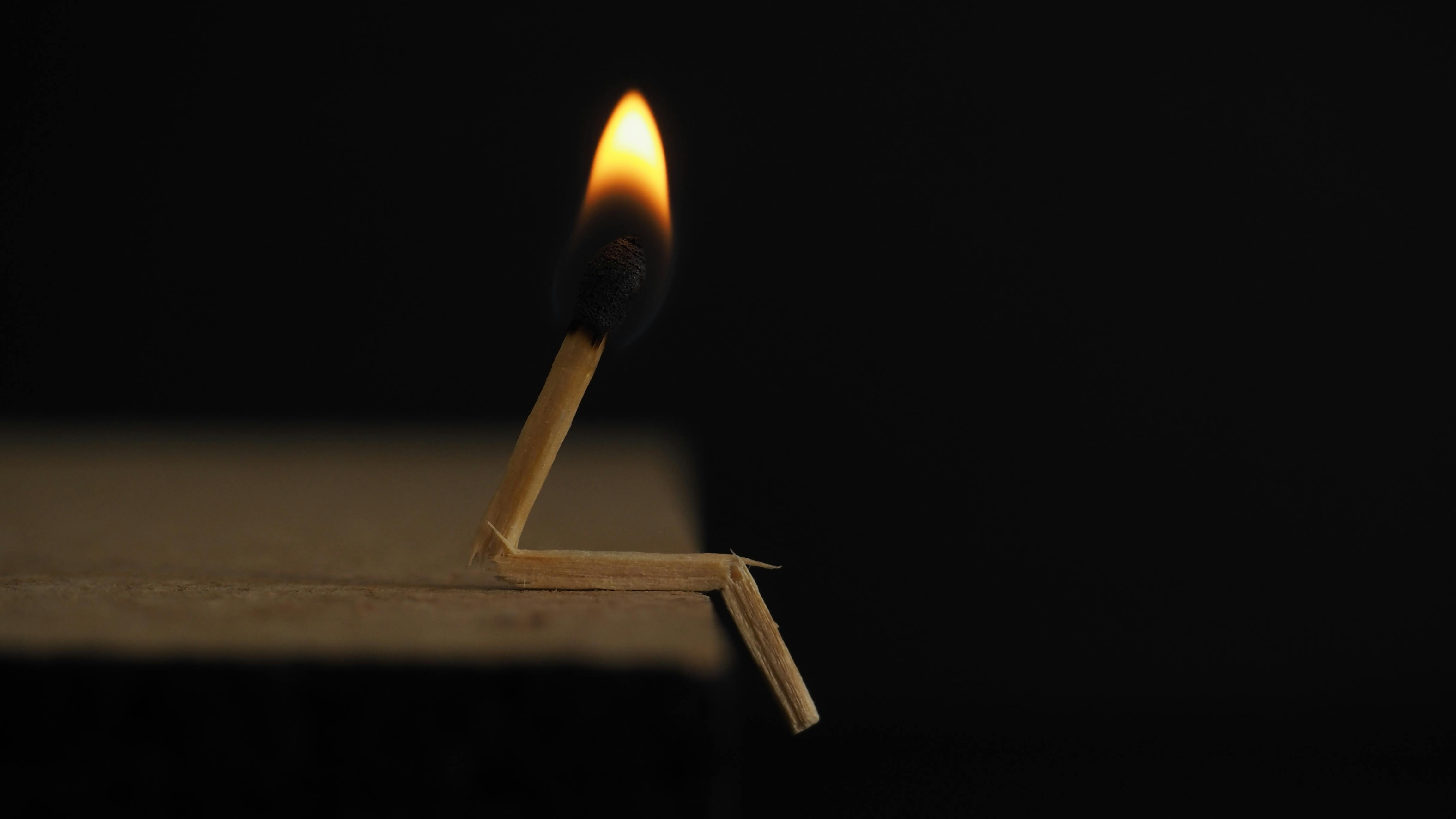 Lighted and broken matchstick on wooden table